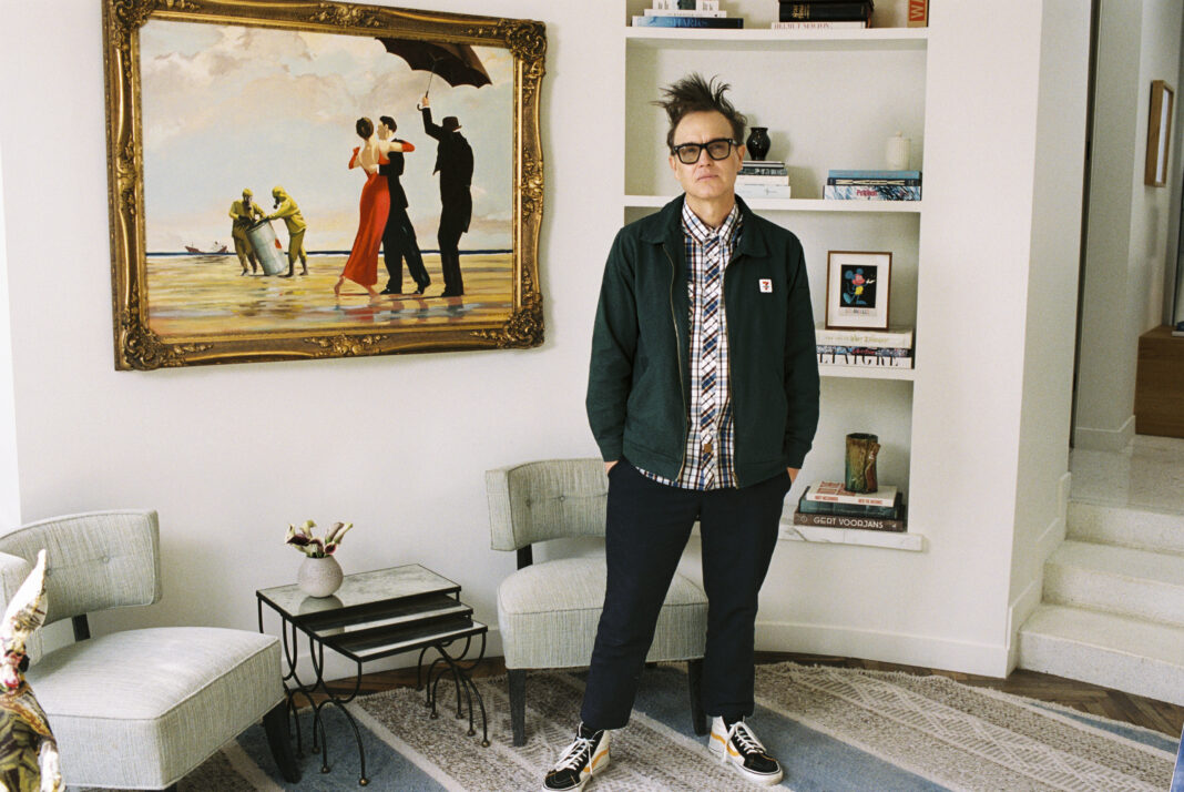 In this undated handout photo provided by Sotheby's, Mark Hoppus of Blink-182 poses by his painting Crude Oil (Vettriano) by Banksy (2005), which is being sold by Sotheby's on March 4 with some of the proceeds going to victims of the Los Angeles wildfires. (Max Montgomery/Sotheby's via AP)